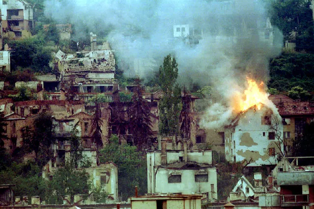 A house is burning down near the Jewish cemetery in Sarajevo, 1994. The house caught fire following a mortar explosion. (Photo by Peter Andrews/Reuters)