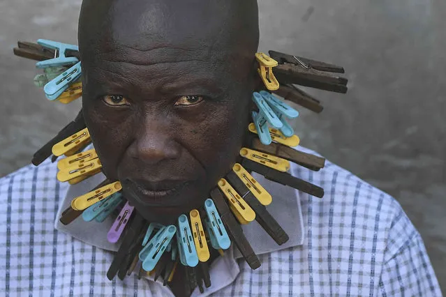A man has clothes pins attached to his head as a penance for passing during a domino game in Port-au-Prince, Haiti, Tuesday, November 9, 2021. For every move he has to pass he would attach another two clothes pins to his head. (Photo by Matias Delacroix/AP Photo)