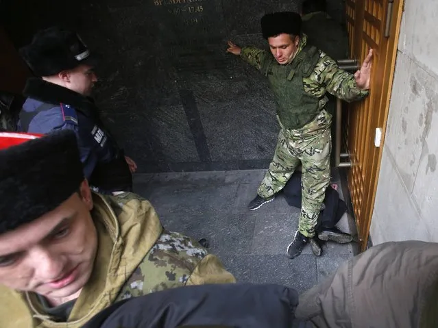 Police and Cossacks detain a Femen women's rights activist, on the ground right, during protest against the situation in the Crimea in front of regional Crimean parliament building in Simferopol. (Photo by Sergei Grits/AP Photo)