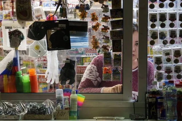 A seller waits for customers as protective masks and gloves are displayed in a kiosk in Moscow, Russia, Thursday, November 18, 2021. (Photo by AP Photo/Stringer)