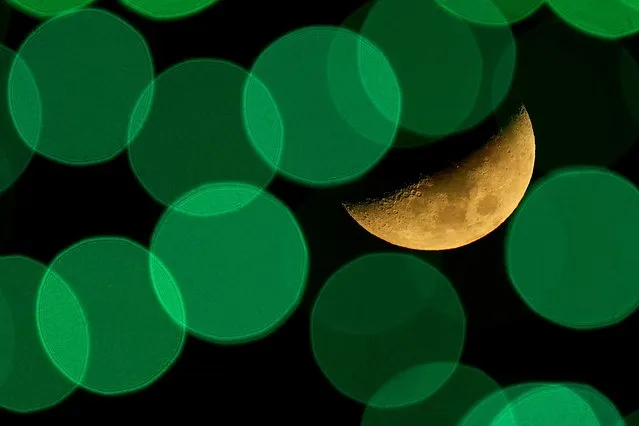 The setting moon is framed by Christmas lights Thursday, December 9, 2021, in Lenexa, Kan. (Photo by Charlie Riedel/AP Photo)