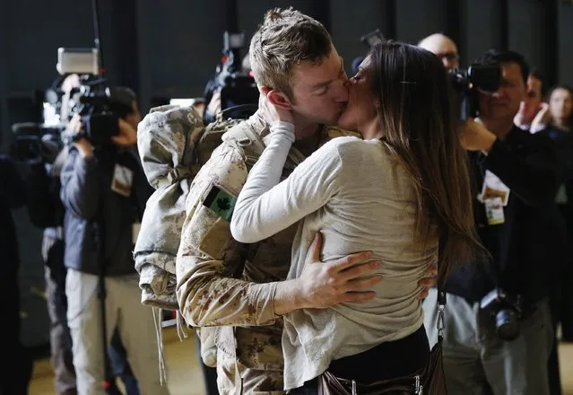 Canadian Army Master Corporal Anthony Alliot (L) kisses Sarah Tooth after arriving from Afghanistan, in Ottawa March 18, 2014. Canada's 12-year mission in Afghanistan has formally ended, according to the military. (Photo by Blair Gable/Reuters)