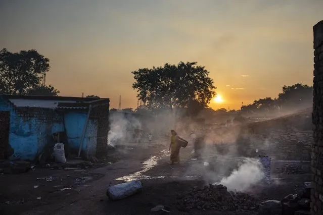 A woman walks past piles of coal burning after scavenging from an open-cast mine near Dhanbad, an eastern Indian city in Jharkhand state, Thursday, September 23, 2021. On Saturday, India asked for a crucial last minute-change to the final agreement at crucial climate talks in Glasgow, calling for the “phase-down” not the "phase-out" of coal power. (Photo by Altaf Qadri/AP Photo)