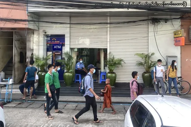 People walk past a bank and an ATM machine in Yangon, Myanmar on November 12, 2021. (Photo by AP Photo/Stringer)