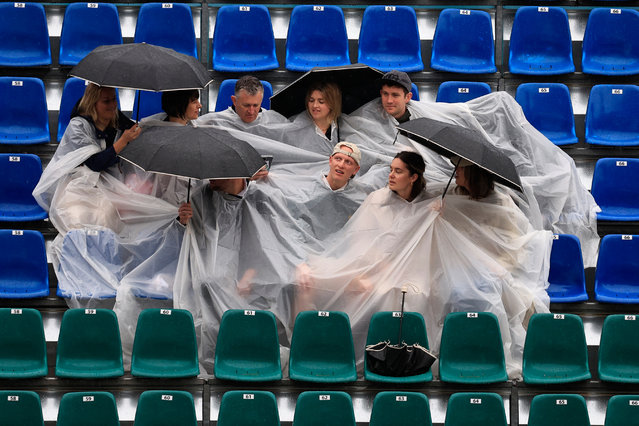 Spectators with umbrellas sit next to empty spectator seats as tennis matches are delayed due to weather conditions, during the Monte Carlo ATP Masters Series Tournament at the Monte Carlo Country Club on April 9, 2024. (Photo by Valéry Hache/AFP Photo)