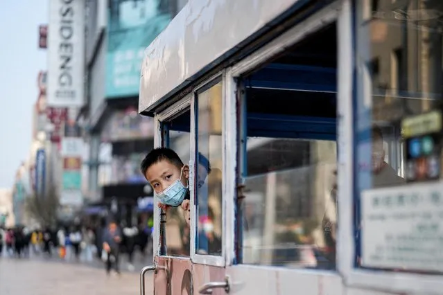 A boy wearing a protective mask is seen in a tourist electric car, following new coronavirus disease (COVID-19) cases in Shanghai, China on February 14, 2022. (Photo by Aly Song/Reuters)