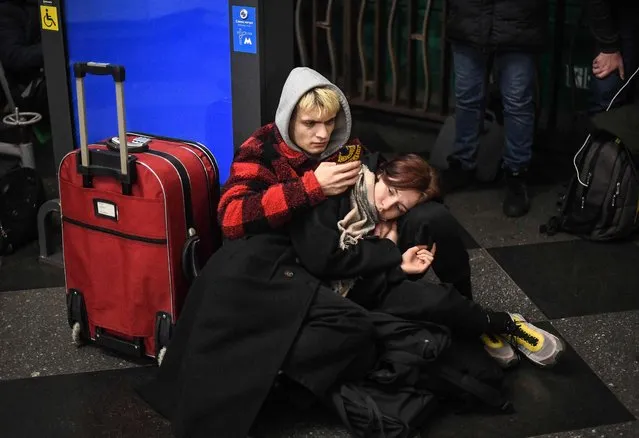 People use their phone as they take shelter in a metro station in Kyiv in the morning of February 24, 2022. Air raid sirens rang out in downtown Kyiv today as cities across Ukraine were hit with what Ukrainian officials said were Russian missile strikes and artillery. (Photo by Daniel Leal/AFP Photo)