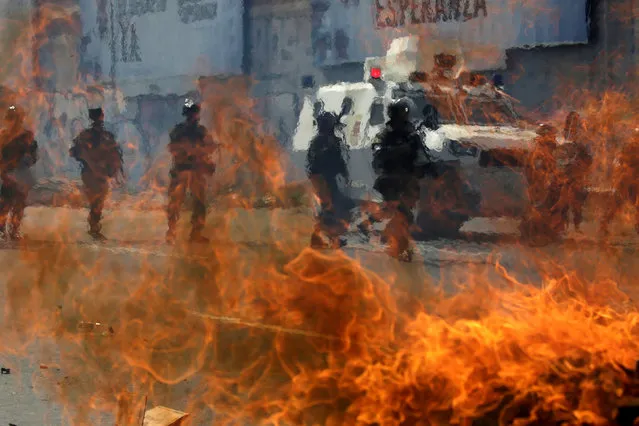 Venezuelan national guards walk behind a burning blockade during clashes with demonstrators during an opposition rally in Caracas, Venezuela, April 6, 2017. (Photo by Marcos Bello/Reuters)