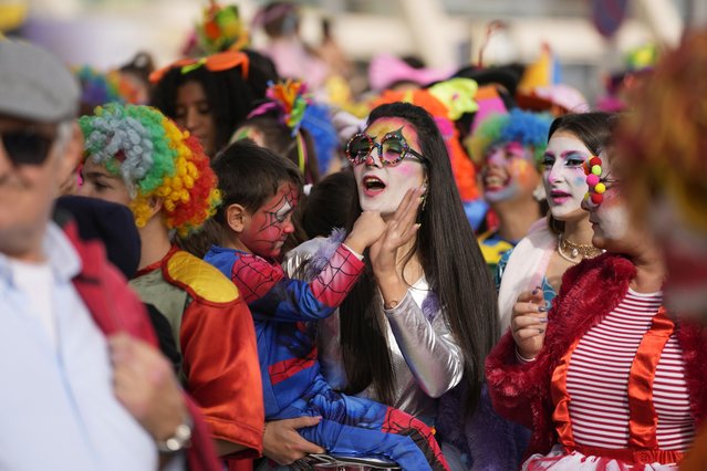 A woman dances with a child during the Clowns Parade in Sesimbra, Portugal, Monday, February 20, 2023. Thousands in clown costumes joined the seaside town's traditional Carnival Monday parade along the waterfront. (Photo by Armando Franca/AP Photo)