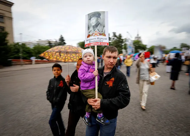 A man with his child hold a portrait of their deceased relative who took part in World War Two during a march at Victory Day commemorations in  Almaty, Kazakhstan, May 9, 2016. (Photo by Shamil Zhumatov/Reuters)