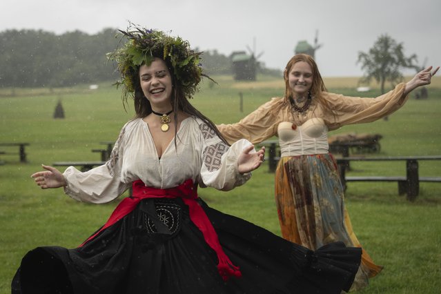 Ukrainian young women dressed in traditional clothing dance under heavy rain at a traditional Midsummer Night celebration near capital Kyiv, Ukraine, Sunday, June 23, 2024. The age-old pagan festival is still celebrated in Ukraine amid the third year of Russia-Ukraine war. (Photo by Efrem Lukatsky/AP Photo)