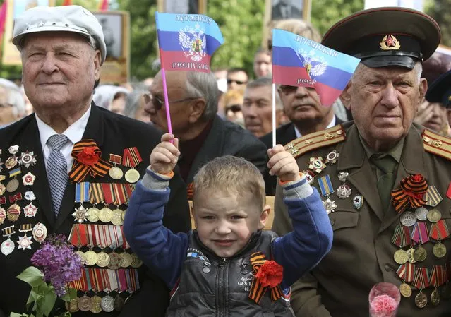 A child holds flags, which read “Lugansk Republic”, as he marks Victory Day with former Soviet servicemen during celebrations in the Eastern Ukrainian city of Lugansk May 9, 2014.  Russian President Vladimir Putin praised the Soviet role in defeating fascism on Friday, the anniversary of the World War Two victory over Nazi Germany, and said those who defeated fascism must never be betrayed. (Photo by Valentyn Ogirenko/Reuters)