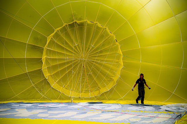 A pilot checks the rigging inside a hot air balloon canopy as they prepare to take off from Queen Square in Bristol during Fiesta Fortnight as part of the Bristol International Balloon Fiesta on Wednesday, August 11, 2021. (Photo by Ben Birchall/PA Images via Getty Images)
