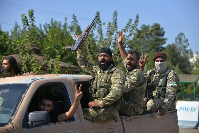 Members of Syrian National Army, known as Free Syrian Army, wave as they drive to cross into Syria near the Turkish border town of Ceylanpinar in Sanliurfa province, Turkey, October 10, 2019. (Photo by Reuters/Stringer)