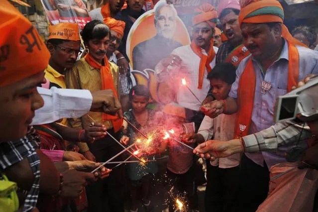 Bharatiya Janata Party (BJP) supporters light firecrackers to celebrate the party's winning performance in the general elections in Varanasi, in the northern Indian state of Uttar Pradesh, Friday, May 16, 2014. (Photo by Rajesh Kumar Singh/AP Photo)