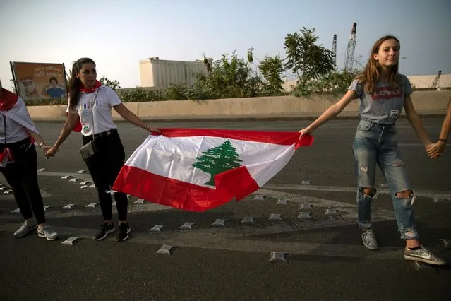 Demonstrators form a human chain during ongoing anti-government protests in Beirut, Lebanon on October 27, 2019. Protesters formed a human chain across Lebanon on Sunday, the eleventh day of unprecedented rallies against politicians accused of corruption and steering the country toward an economic collapse unseen since the 1975-90 civil war. (Photo by Alkis Konstantinidis/Reuters)
