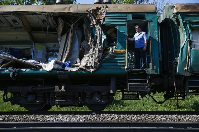 A train conductor stands at a door of a damaged railway car at the site of train collision near the city of Naro-Fominsk outside Moscow Tuesday May 20, 2014. The Interior Ministry said the accident happened when several cars of a cargo train derailed and hit a passenger train near Naro-Fominsk, a town 50 kilometers (30 miles) southwest of Moscow. (Photo by Pavel Golovkin/AP Photo)