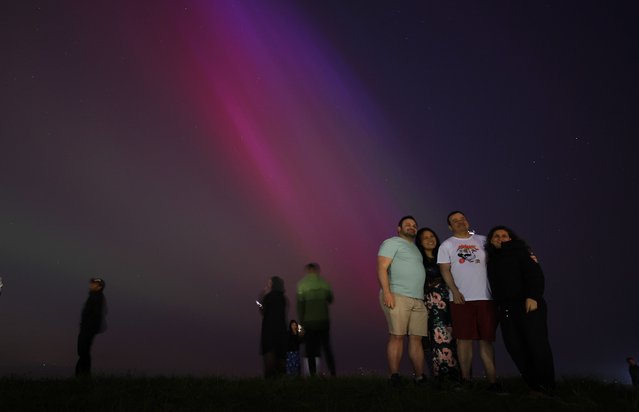 People pose for a photograph with the Aurora Borealis, also known as the Northern Lights, in Crosby, Britain, 10 May 2024. The National Oceanic and Atmospheric Administration (NOAA) of America has warned that the strongest geomagnetic storm for 20 years is set to hit Earth, making the Aurora Borealis, or Northern Lights, visible at much lower geomagnetic latitudes than usual. (Photo by Adam Vaughan/EPA/EFE/Rex Features/Shutterstock)