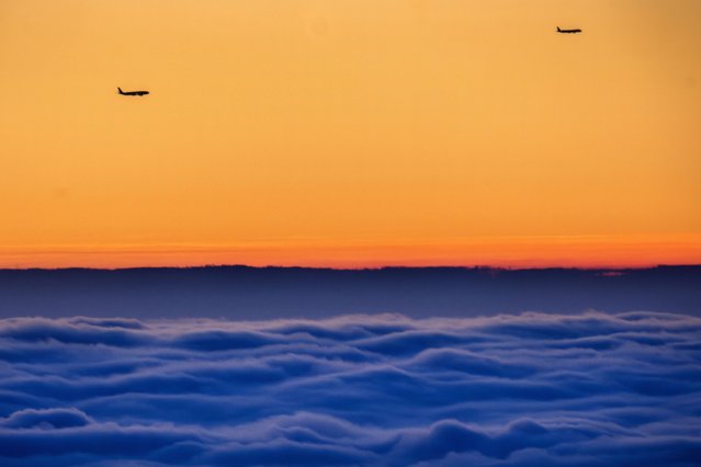 Planes fly over the fog covering the city as they approach the airport in Frankfurt, Germany, Monday, December 18, 2023. (Photo by Michael Probst/AP Photo)