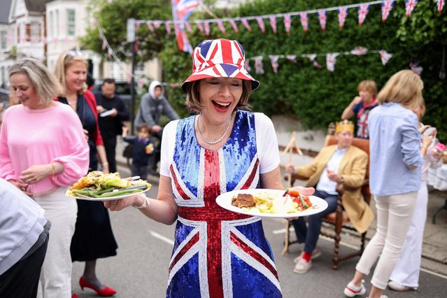 Sophie Graham carries plates of food at a Big Lunch event to celebrate the coronation of Britain's King Charles, in Napier Avenue in Fulham, London, Britain on May 7, 2023. (Photo by Kevin Coombs/Reuters)