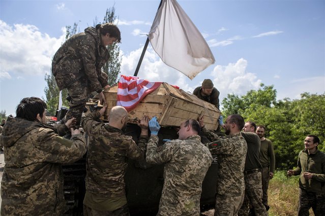 Ukrainian servicemen carry a coffin with the body of a person who is considered to be former U.S. Army soldier Nicholas Maimer, killed in the frontline town of Bakhmut, after prisoners of war (POWs) swap, amid Russia's attack on Ukraine, in Donetsk region, Ukraine on May 25, 2023. (Photo by Yevhenii Zavhorodnii/Reuters)