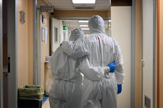In this file photo taken on April 20, 2020 Doctor Marco (R) and nurse Manu, wearing protective gear react at the end of their shift in a corridor of the level intensive care unit, treating COVID-19 patients, at the San Filippo Neri hospital in Rome. The World Health Organization said on October 21, 2021 that 80,000 to 180,000 health care workers may have been killed by Covid-19 up to May this year, insisting they should be prioritised for vaccination. (Photo by Alberto Pizzoli/AFP Photo)