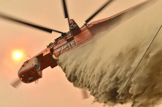 A helicopter drops fire retardent to protect a property in Balmoral, 150 kilometres southwest of Sydney on December 19, 2019. A state of emergency was declared in Australia's most populated region on December 19, as a record heat wave fanned unprecedented bushfires. (Photo by Peter Parks/AFP Photo)