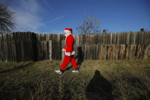 A charity worker wearing a Santa Claus costume walks after delivering Christmas presents to a poor family on the outskirts of Brasov, Romania, Sunday, December 15, 2019. (Photo by Vadim Ghirda/AP Photo)