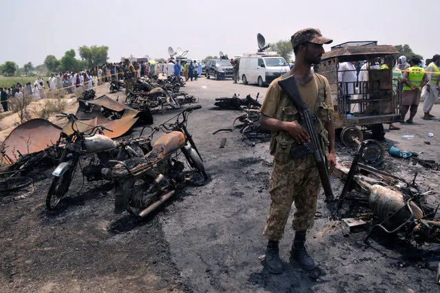 A soldier stands guard amid burnt out cars and motorcycles at the scene of an oil tanker explosion in Bahawalpur, Pakistan June 25, 2017. (Photo by Reuters/Stringer)