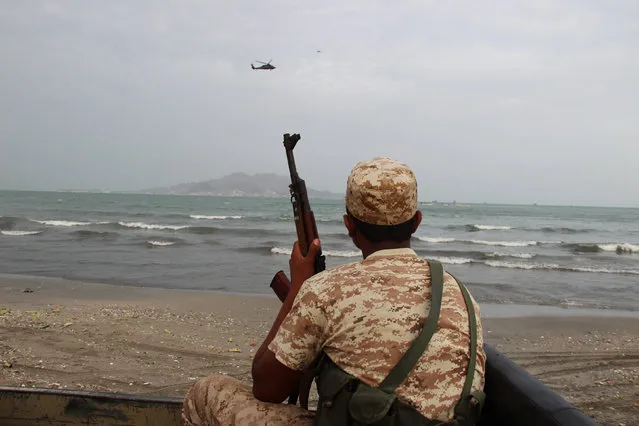 A Yemeni soldier looks as a UAE military helicopter hover over the sea during the search for the wreckage of a crashed UAE military helicopter off the southern city of Aden, Yemen, June 13, 2016. (Photo by Fawaz Salman/Reuters)