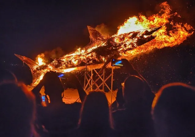 Artist Robert Pantaleo's 25-foot-long metal sculpture of a mako shark, filled with palm fronds, burns on the beach at the Guy Harvey Outpost Islander Resort in Islamorada, Florida  June 18, 2016. The bonfire was a facet of the Blazing Mako Festival in the Florida Keys featuring a fishing tournament as well as artist and marine conservation exhibits. Picture taken June 18, 2016. (Photo by Ron Modra/Reuters/Florida Keys News Bureau)