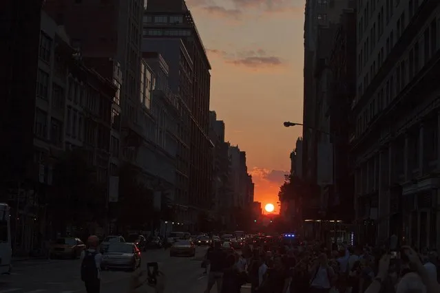People take pictures at sunset, during the bi-annual occurrence “Manhattanhenge” in New York July 11, 2014. Manhattanhenge, coined by astrophysicist Neil deGrasse Tyson, occurs when the setting sun aligns itself with the east-west grid of streets in Manhattan, allowing the sun to shine down all streets at the same time. (Photo by Eduardo Munoz/Reuters)