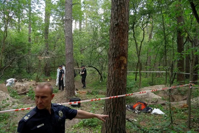 A police officer points at a site of a mass grave of people who, Ukrainian police say, were killed and buried at a position of Russian troops during Russia's invasion near the village of Vorzel, in Bucha district, Kyiv region, Ukraine on June 13, 2022. (Photo by Valentyn Ogirenko/Reuters)