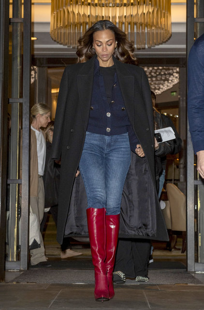 Zoe Saldana is pictured leaving her London hotel on October 10, 2024. The American actress wore a black trench coat, dark blouse, jeans, and knee high red boots. (Photo by The Image Direct)