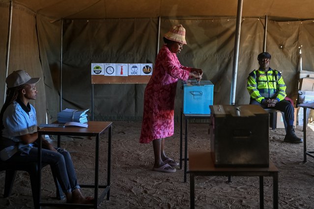 A voter (C) casts her ballot as an electoral official (L) and a Botswana Police officer (R) look on at the Gaborone Block 8 polling station in Gaborone on October 30, 2024, during Botswana's general election. (Photo by Monirul Bhuiyan/AFP Photo)