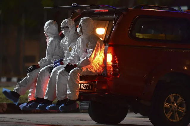 In this photo taken and released by Malaysia's Ministry of Health, health workers wearing full protective suits sit on a vehicle as they wait for the arrival of evacuated Malaysian from China's Wuhan, the epicenter of the coronavirus outbreak, at Kuala Lumpur International Airport in Sepang, Malaysia, Wednesday, February 26, 2020. U.S. health officials warned Tuesday that the burgeoning coronavirus is certain to spread more widely in the country at some point, even as their counterparts in Europe and Asia scrambled to contain new outbreaks of the illness. (Photo by Muzzafar Kasim/Malaysia's Ministry of Health via AP Photo)