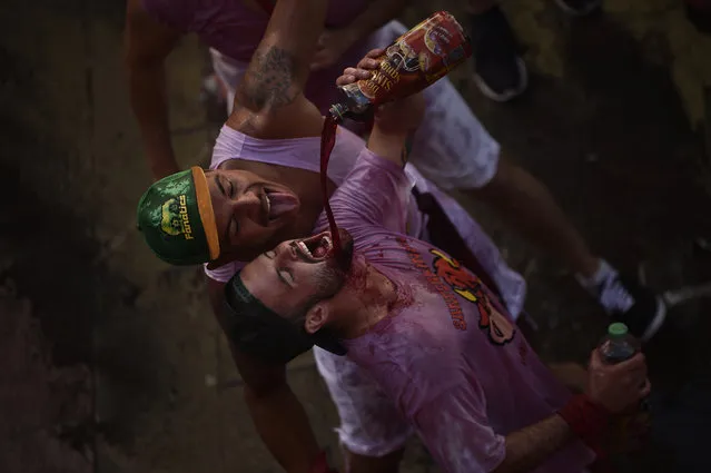 Revelers drink, during the launch of the “Chupinazo” rocket, to celebrate the official opening of the 2016 San Fermin Fiestas, in Pamplona, northern Spain, Wednesday, July 6, 2016. Revelers from around the world kick off the festival with a messy party in the Pamplona town square, one day before the first of eight days of the running of the bulls. (Photo by Alvaro Barrientos/AP Photo)