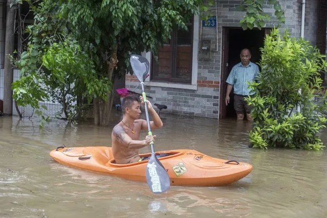 A man paddles a kayak along a flooded street caused by Typhoon Hato in Guangzhou in southern China's Guangdong province Wednesday August 23, 2017.  Thousands of people were evacuated from parts of the mainland coast ahead of the storm's arrival, China's official Xinhua News Agency reported. (Photo by Chinatopix via AP Photo)