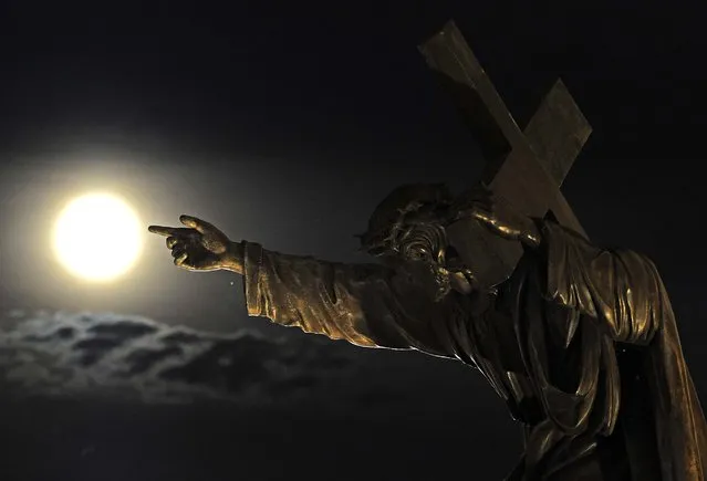 The Supermoon rises above a Jesus Christ statue in front of the Holy Cross church in Warsaw, Poland. (Photo by Alik Keplicz/Associated Press)