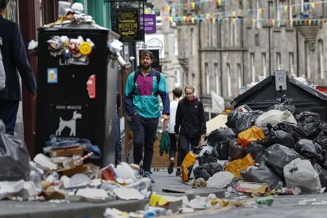 Members of the public walk past a large piles of rubbish on August 29, 2022 in Edinburgh, Scotland. Bin collections have been suspended in the Scottish capital for 10 days as waste workers have been on strike. Normal shifts will resume tomorrow here, but 13 more Scottish councils are scheduled to begin similar strike action on Wednesday. A second wave of waste-worker strikes in Edinburgh is scheduled from September 7-13, unless there's progress in talks between unions and local authorities. (Photo by Jeff J. Mitchell/Getty Images)
