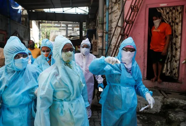 Healthcare workers enter a resedential area to check residents during a nationwide lockdown to slow the spreading of the coronavirus disease (COVID-19), in Mumbai, April 20, 2020. (Photo by Francis Mascarenhas/Reuters)