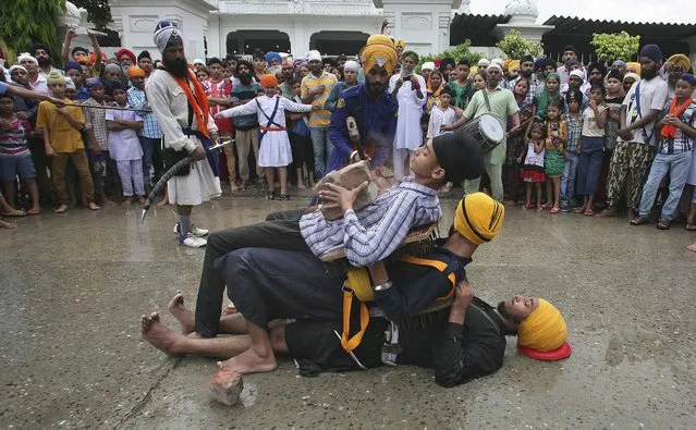 A Nihang or Sikh warrior uses a hammer to break bricks on the stomach of another Sikh as they perform Gatkha, a traditional form of martial arts, during the celebrations of the 410th anniversary of the installation of the Guru Granth Sahib, the religious book of Sikhs, in the northern Indian city of Amritsar September 1, 2014. (Photo by Munish Sharma/Reuters)