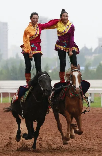Tibetan women stand on their horses as they give an equestrian performance during the 10th Chinese Traditional Games of Ethnic Nationalities in Erdos, Inner Mongolian Autonomous Region, China, August 10, 2015. (Photo by Reuters/China Daily)