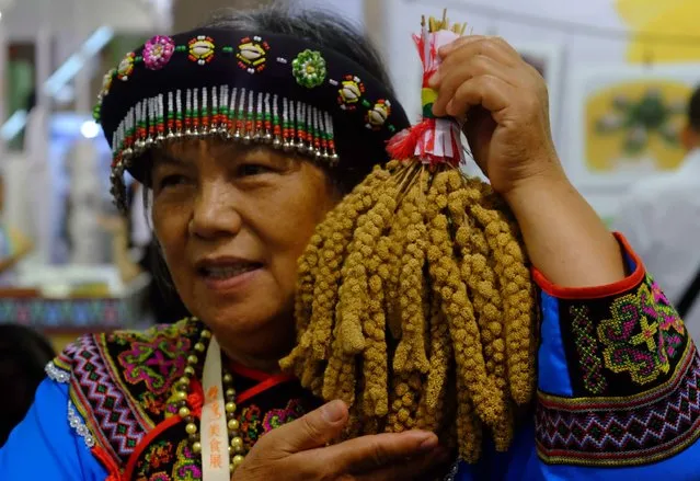 A woman dressed in traditional aboriginal costume holds up millets during the 2016 Taiwan Culinary Exhibition at the World Trade Center in Taipei on August 5, 2016. More than 800 booths from Taiwan, China and Japan are taking part in the food exhibition from August 5 to 8. (Photo by Sam Yeh/AFP Photo)