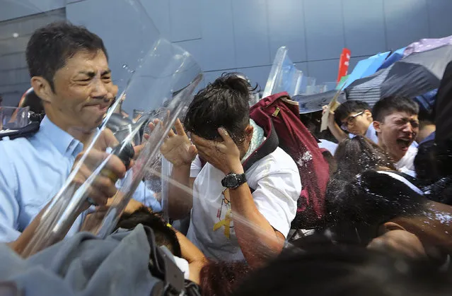 Riot policemen use pepper spray to young pro-democracy activists who forced their way into Hong Kong government headquarters during a demonstration in Hong Kong, early Saturday, September 27, 2014. The scenes of disorder came at the end of a weeklong strike by students demanding China's communist leaders allow residents to directly elect a leader of their own choosing in 2017. (Photo by AP Photo/Apple Daily)