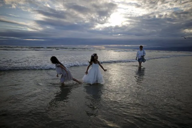 Gena Lindenbaum, 50, (R) and Audrey Klein, 5, (C) walk in the Pacific Ocean during the Nashuva Spiritual Community Jewish New Year celebration on Venice Beach in Los Angeles, California, United States September 14, 2015. (Photo by Lucy Nicholson/Reuters)