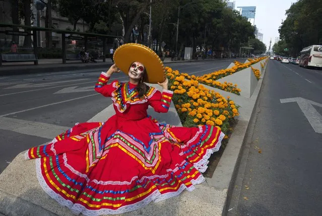 A woman fancy dressed as the character of La Catrina poses before taking part in the Catrinas Parade, commemorating the Day of the Dead, in Mexico City, on October 23, 2022. (Photo by Claudio Cruz/AFP Photo)