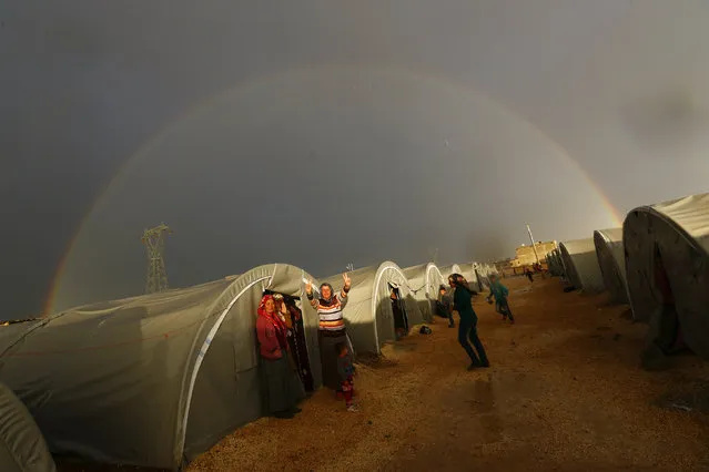 A Kurdish refugee from the Syrian town of Kobani shows victory sign as a rainbow forms over the camp in the southeastern town of Suruc, Sanliurfa province, October 16, 2014. The United States is bombing targets in Kobani for humanitarian purposes to relieve defenders of the Syrian town and give them time to organize against Islamic State militants, a senior U.S. official said on Wednesday. (Photo by Kai Pfaffenbach/Reuters)