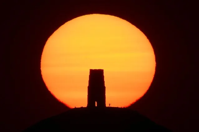 A person views the sun rise from beside the remains of Saint Michael's Church on top of Glastonbury Tor, as the hottest day so far of the summer in Britain is predicted, in Glastonbury, south west Britain on June 24, 2020. (Photo by Toby Melville/Reuters)