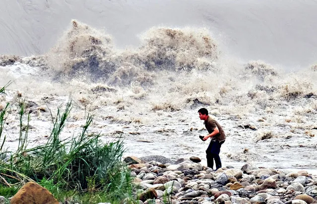 A local resident collects stones from the Xindian river after Typhoon Dujuan passed in the New Taipei City on September 29, 2015. Super typhoon Dujuan killed two and left more than 300 injured in Taiwan before making landfall in China. (Photo by Sam Yeh/AFP Photo)